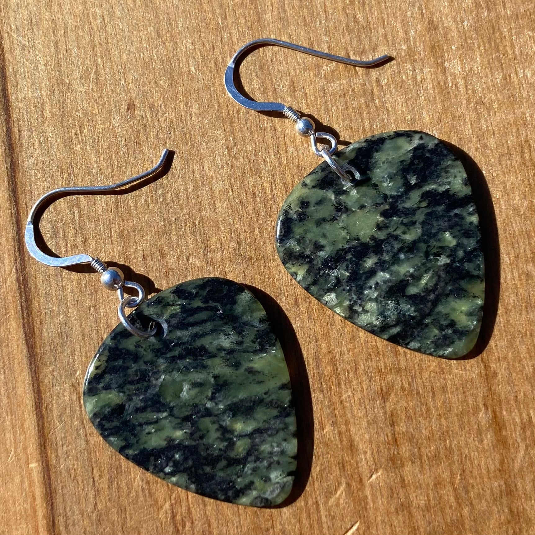 Guitar pick earrings hand-carved from New Zealand Douglas Creek pounamu (greenstone) fitted with sterling silver. Front.