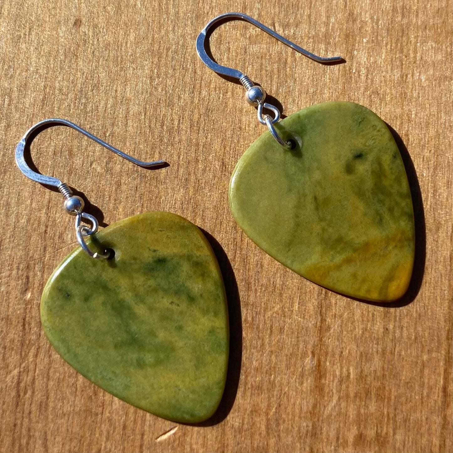 Guitar pick earrings hand-carved from New Zealand Marsden Flower Jade pounamu (greenstone) fitted with sterling silver. Front.