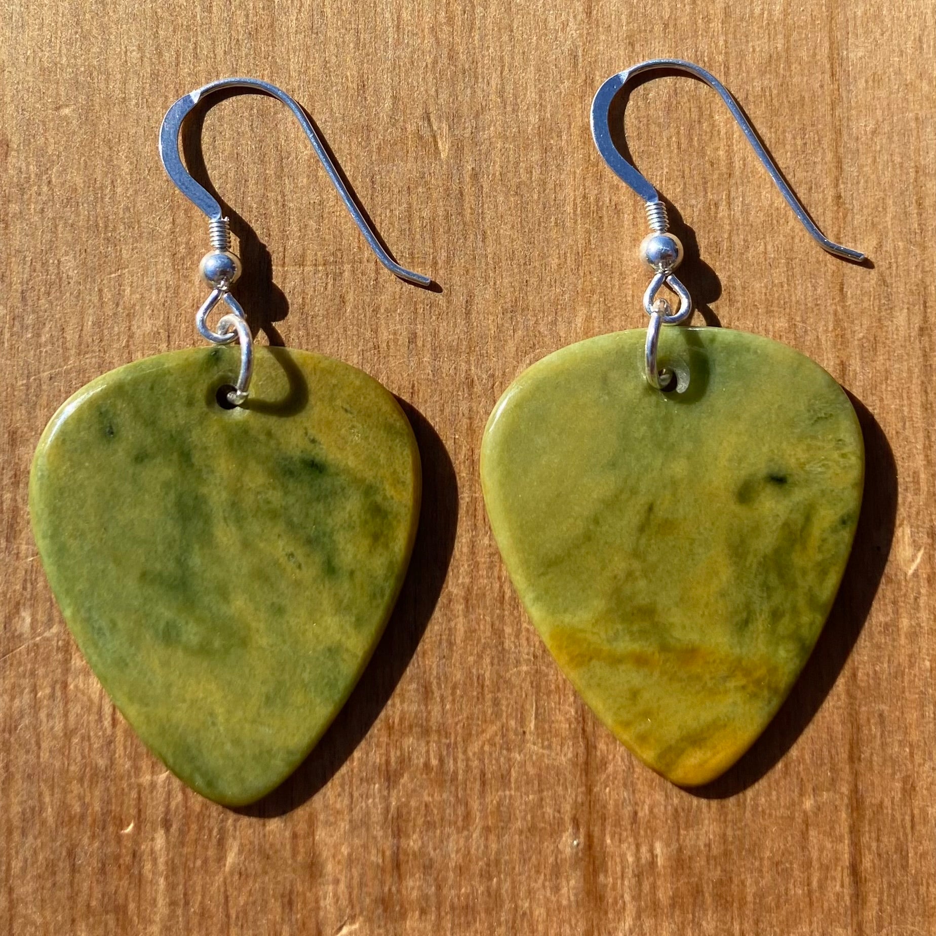 Guitar pick earrings hand-carved from New Zealand Marsden Flower Jade pounamu (greenstone) fitted with sterling silver. Front.