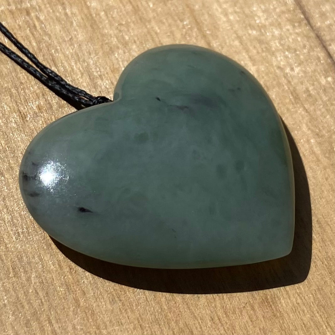 Heart shaped pendant hand-carved from New Zealand inanga pounamu (greenstone). Angle.