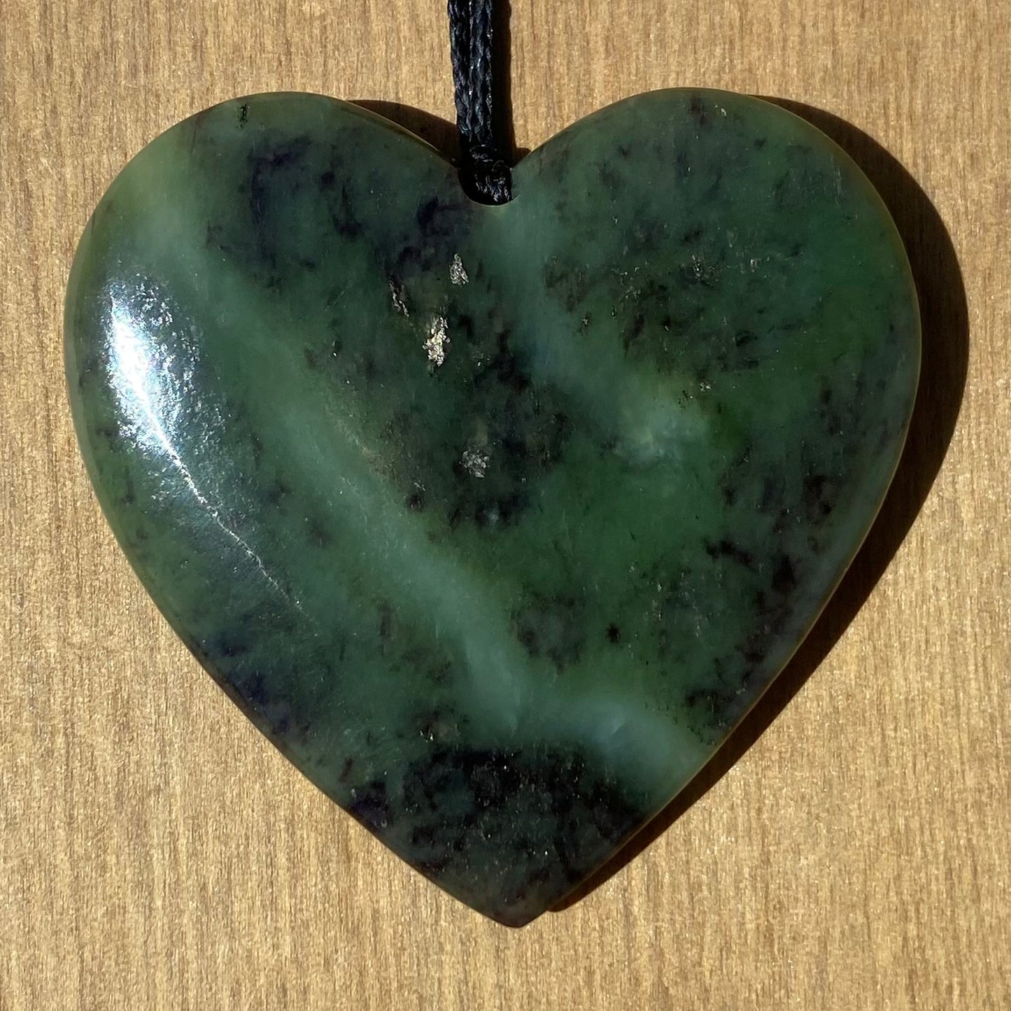 Heart pendant hand-carved from New Zealand totoweka pounamu (greenstone). Front.