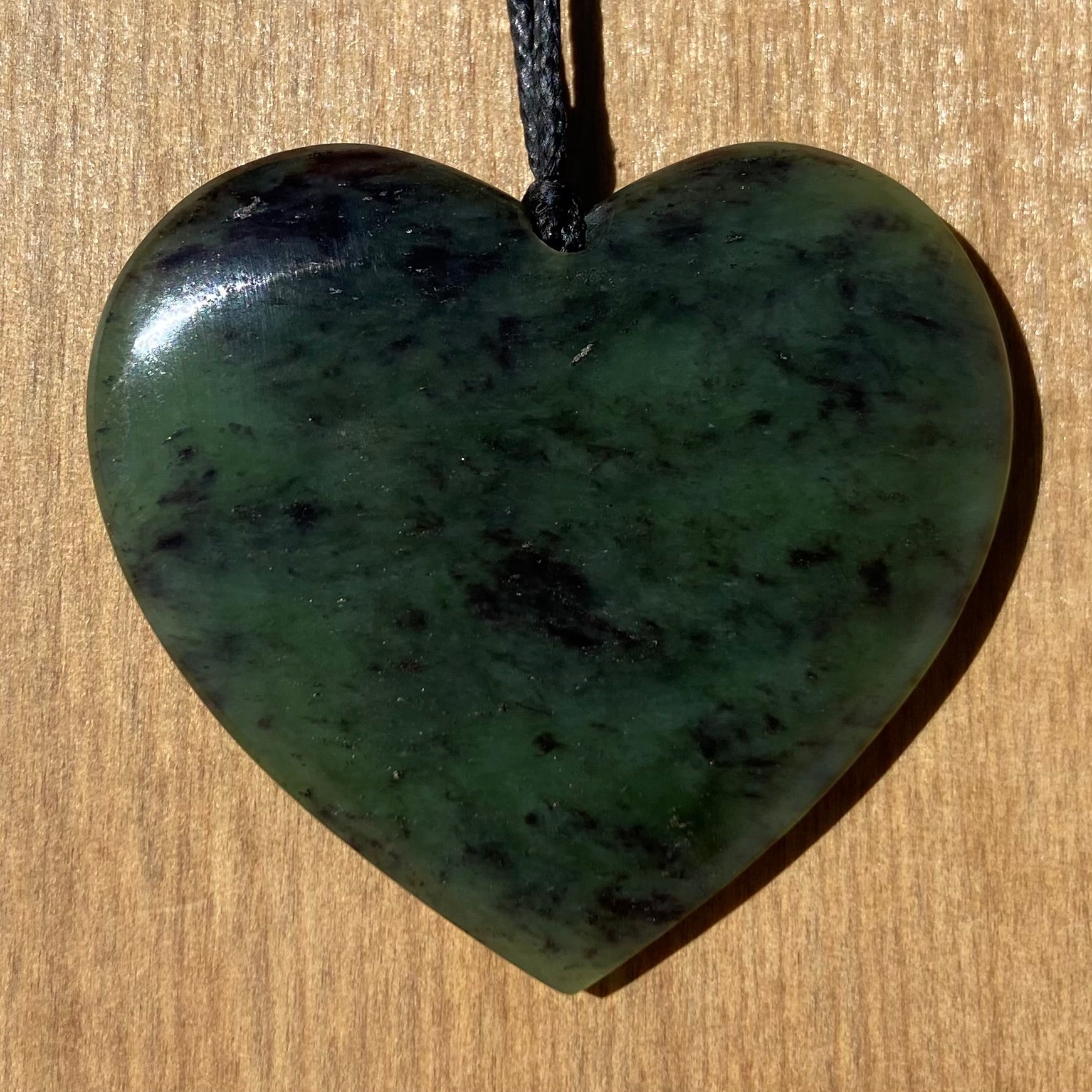 Heart pendant hand-carved from New Zealand totoweka pounamu (greenstone). Front.