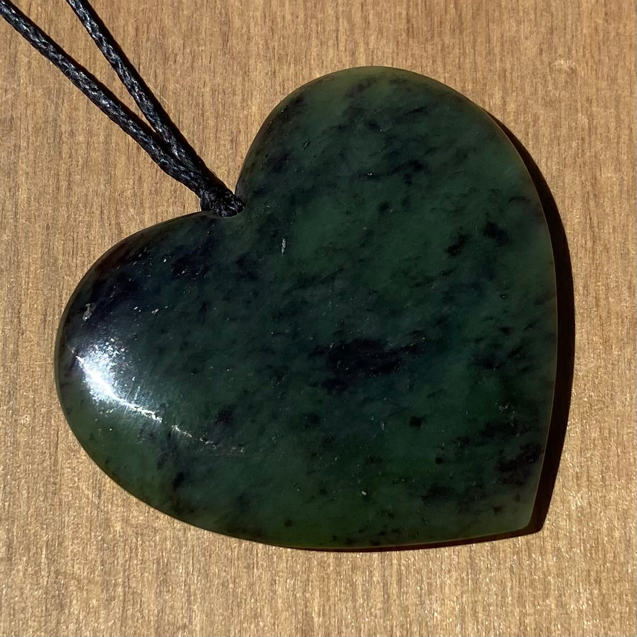 Heart pendant hand-carved from New Zealand totoweka pounamu (greenstone). Angle.