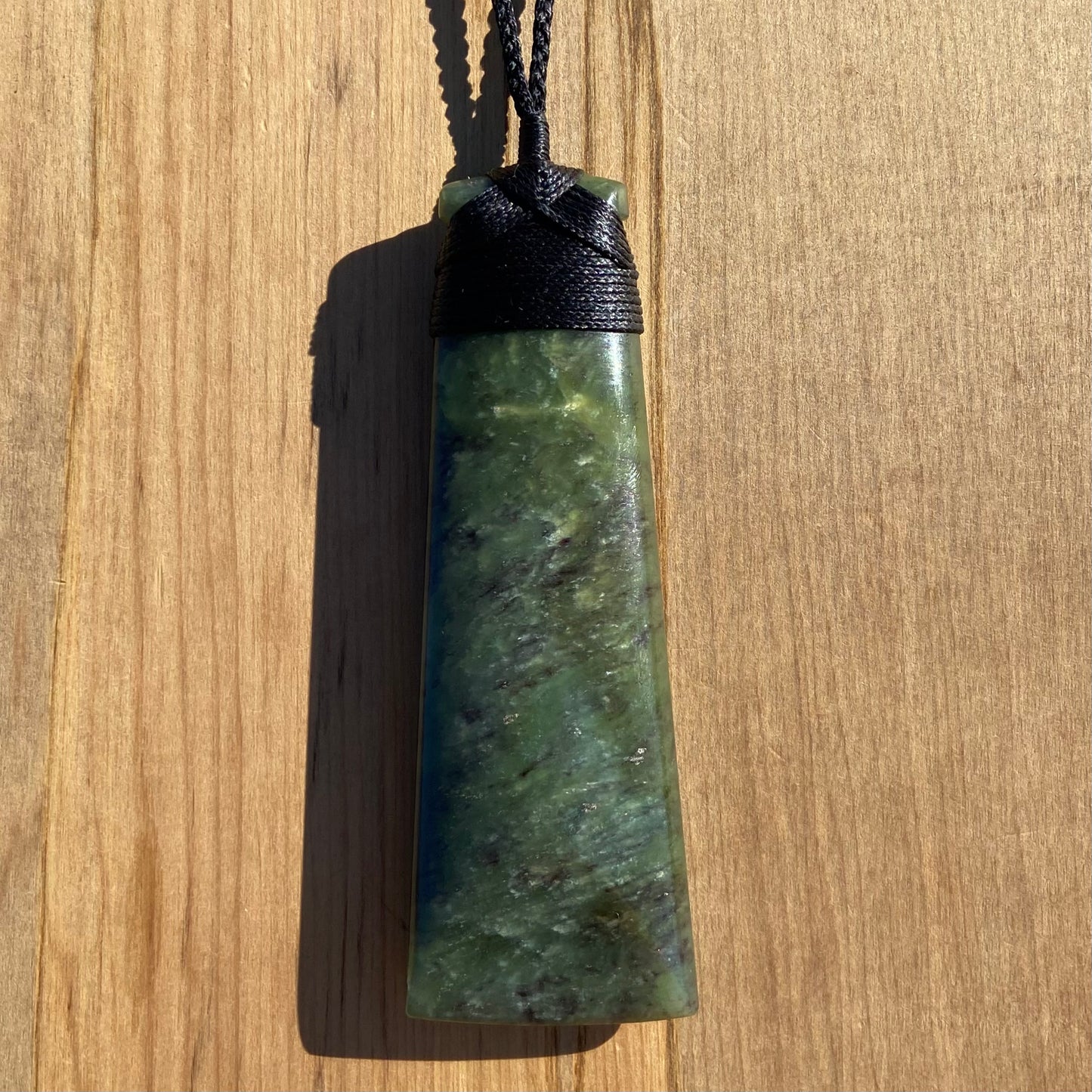 Bound toki pendant hand-carved from New Zealand totoweka pounamu (greenstone). Front.