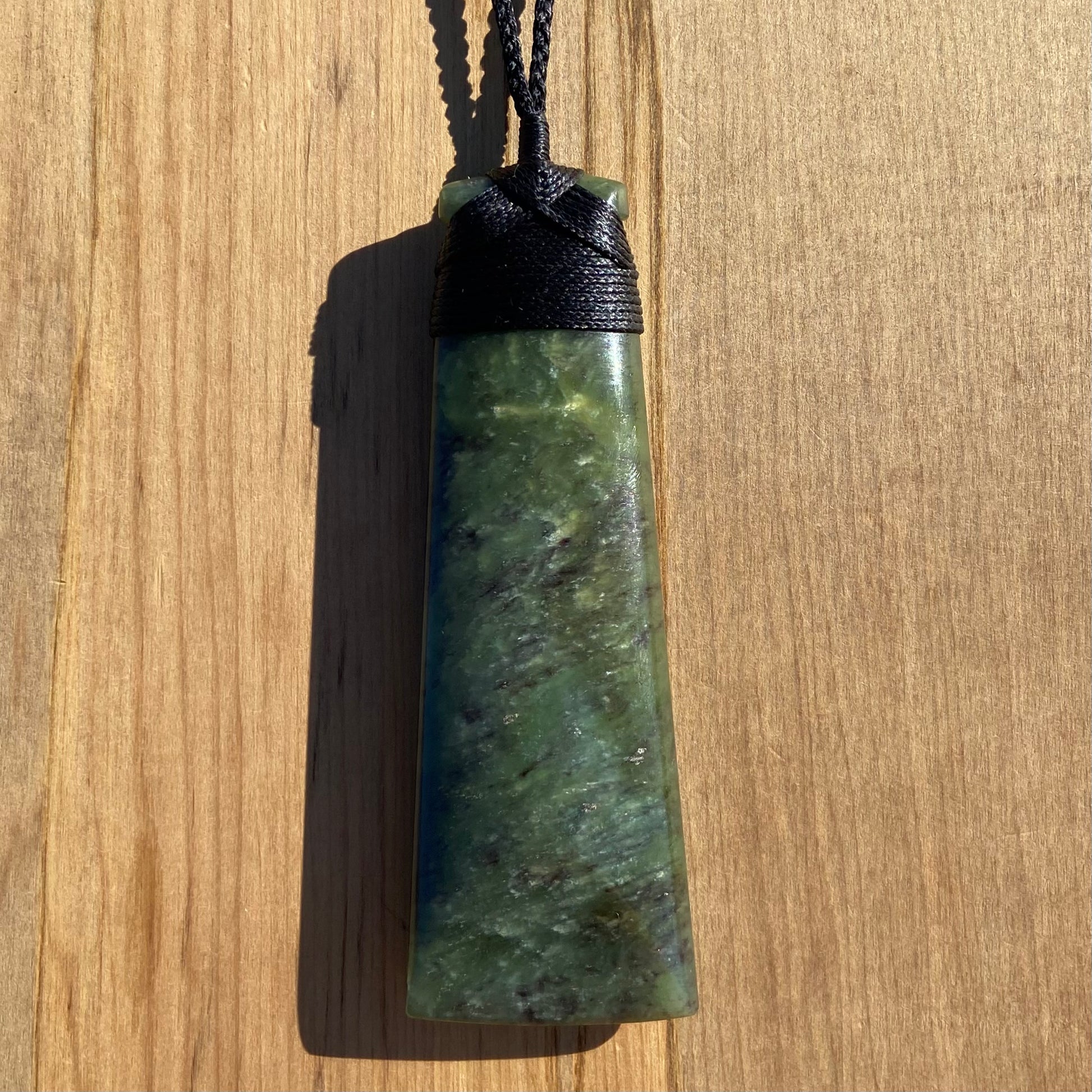 Bound toki pendant hand-carved from New Zealand totoweka pounamu (greenstone). Front.